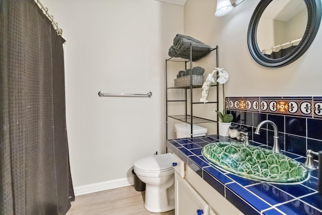 full bathroom featuring wood finished floors, toilet, vanity, baseboards, and curtained shower
