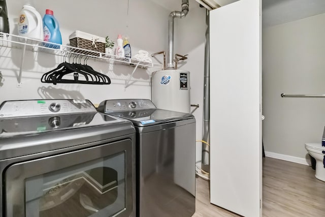 laundry area with light wood finished floors, washer and dryer, water heater, and baseboards