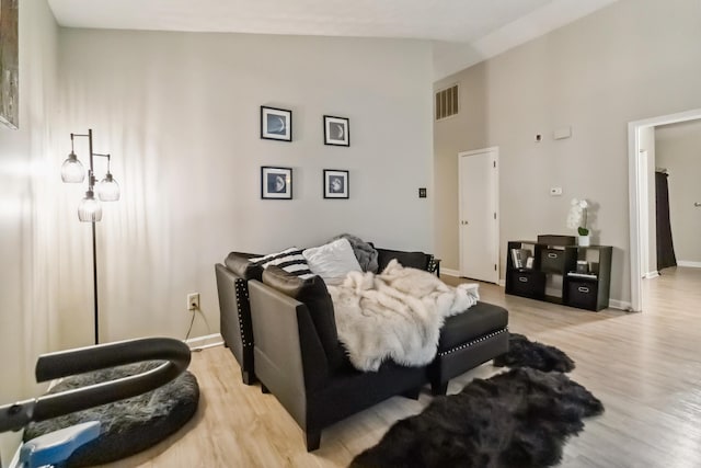 living area featuring visible vents, high vaulted ceiling, light wood finished floors, and baseboards