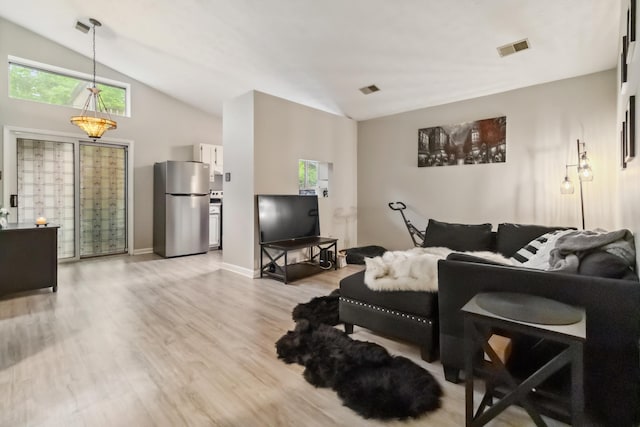 living room featuring visible vents, light wood finished floors, and vaulted ceiling