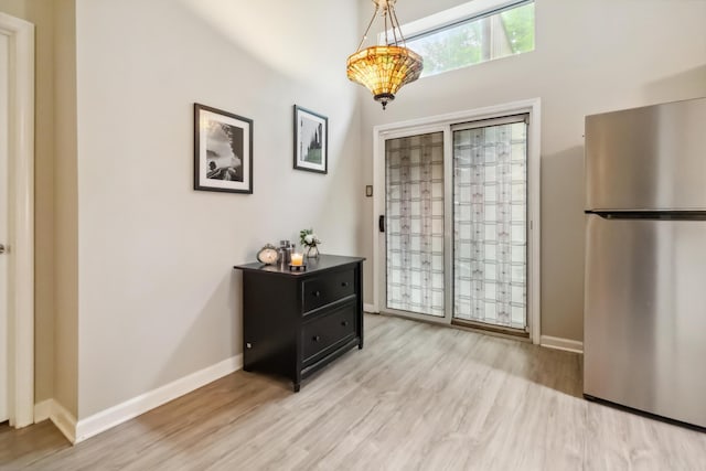 doorway to outside featuring baseboards and light wood finished floors