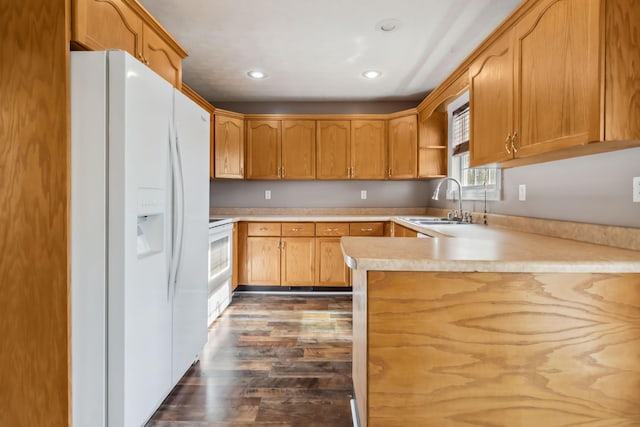 kitchen featuring white refrigerator with ice dispenser, light countertops, a sink, dark wood-style floors, and a peninsula