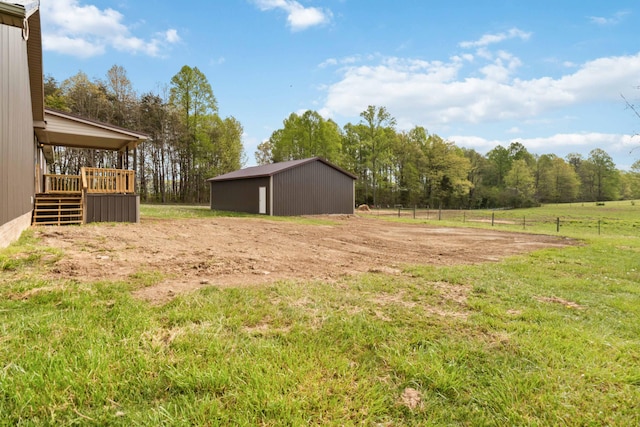 view of yard featuring fence, a pole building, a wooden deck, and an outbuilding