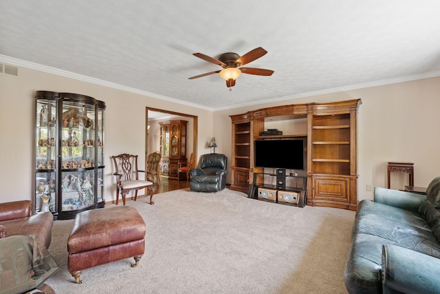 living room with carpet flooring, ceiling fan, visible vents, and ornamental molding