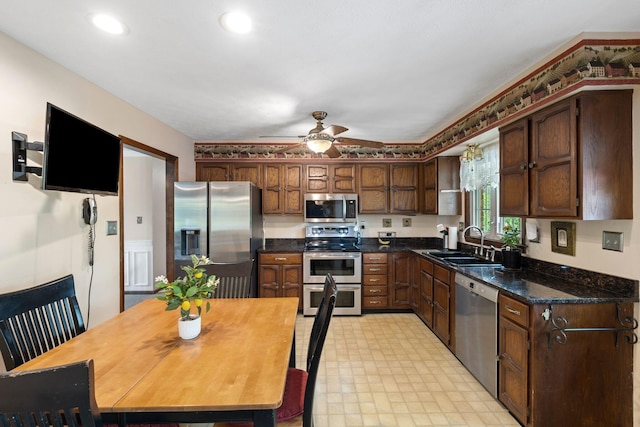 kitchen featuring a ceiling fan, dark countertops, light floors, a sink, and stainless steel appliances
