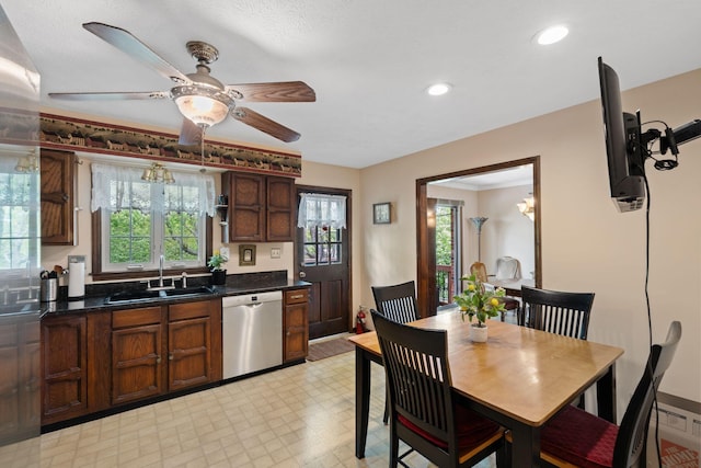 kitchen with dark countertops, a wealth of natural light, a sink, and dishwasher