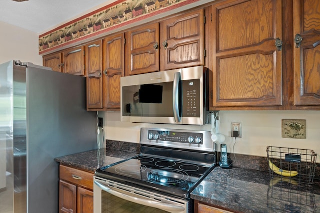 kitchen with dark stone countertops, brown cabinets, and stainless steel appliances