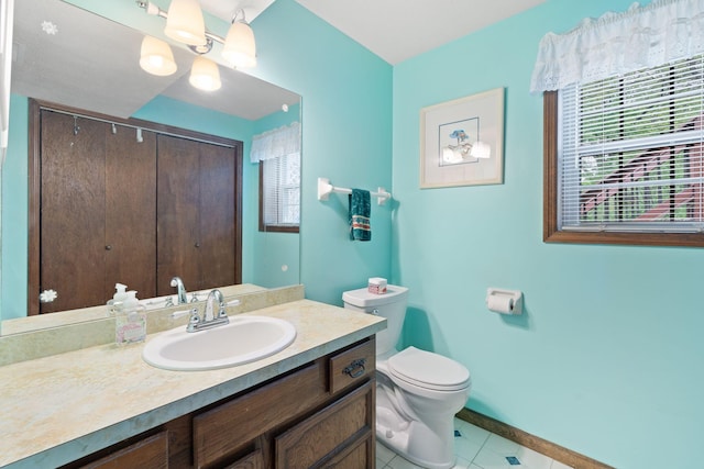 bathroom featuring toilet, tile patterned floors, baseboards, and vanity