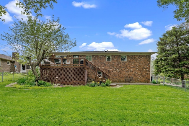 rear view of property featuring a deck, stairway, brick siding, a fenced backyard, and a yard