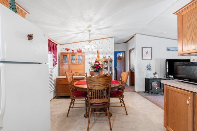 dining space featuring a wood stove, ornamental molding, an inviting chandelier, and light floors