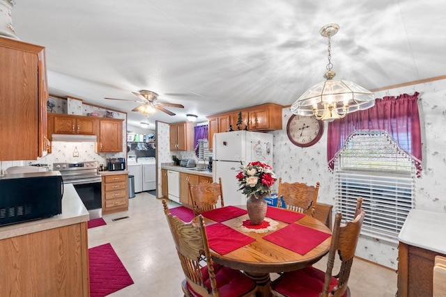 dining room with lofted ceiling, washer and dryer, a ceiling fan, and wallpapered walls
