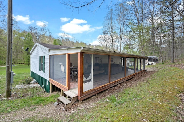 back of house featuring a sunroom and a lawn