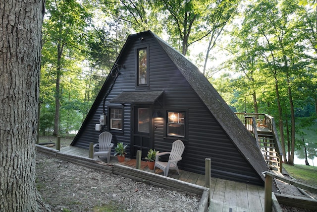 view of side of home with stairway, a shingled roof, and a wooden deck