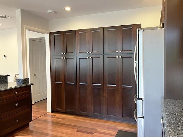 3426 Pepperhill Rd, Lexington, KY 40502 - interior space featuring freestanding refrigerator, light wood finished floors, dark stone counters, dark brown cabinetry, and recessed lighting