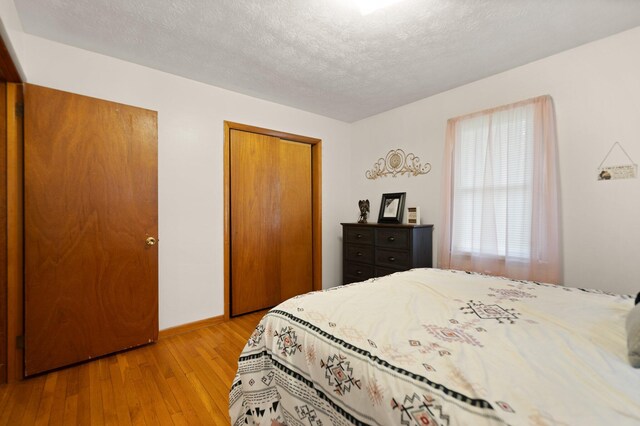 507 Holman Dr, Stanton, KY 40380 - bedroom with light wood-style floors, a closet, baseboards, and a textured ceiling