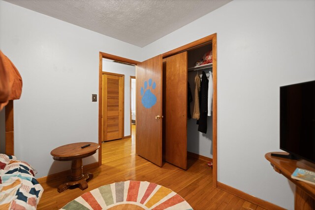 507 Holman Dr, Stanton, KY 40380 - bedroom with light wood-style flooring, a closet, a textured ceiling, and baseboards
