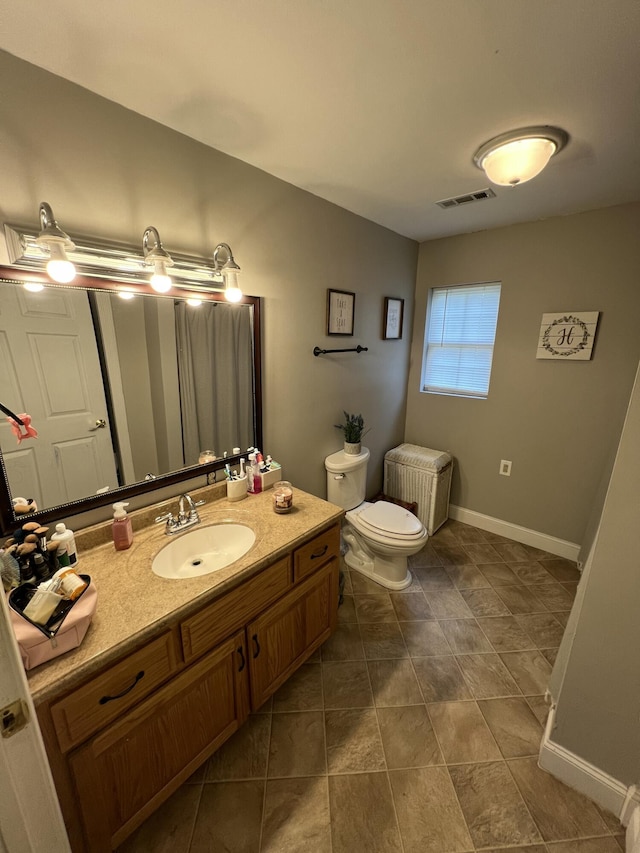 bathroom with visible vents, toilet, vanity, and baseboards