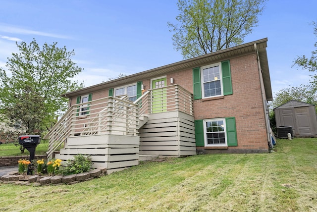 view of front facade with brick siding, a storage shed, stairway, a front yard, and an outdoor structure