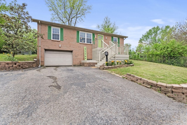 bi-level home with fence, an attached garage, brick siding, a front yard, and driveway