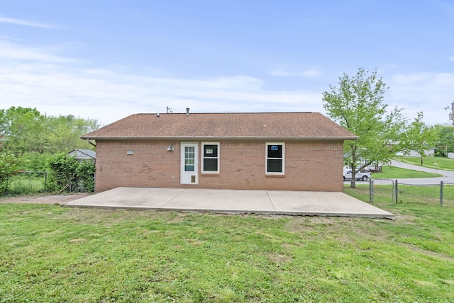 rear view of house with roof with shingles, brick siding, a fenced backyard, a patio area, and a lawn