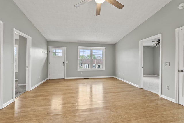 unfurnished living room featuring ceiling fan, vaulted ceiling, baseboards, and light wood finished floors