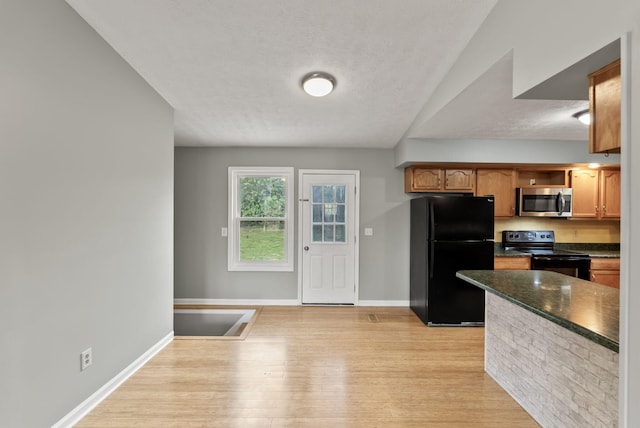 kitchen featuring a textured ceiling, dark countertops, baseboards, black appliances, and light wood-style flooring