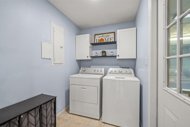 washroom featuring cabinet space, baseboards, light tile patterned floors, washer and clothes dryer, and electric panel
