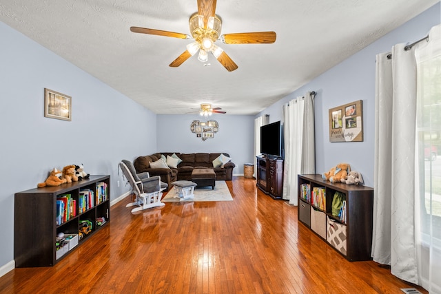 living room featuring baseboards, ceiling fan, and hardwood / wood-style flooring
