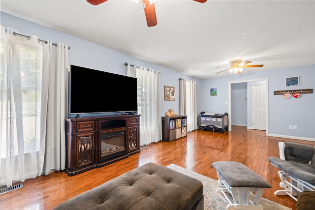 living area featuring a ceiling fan, visible vents, and hardwood / wood-style floors