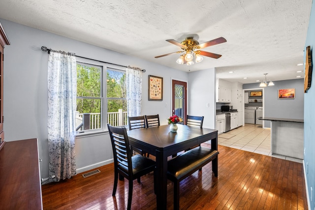 dining room featuring a ceiling fan, a textured ceiling, visible vents, light wood finished floors, and washer and dryer