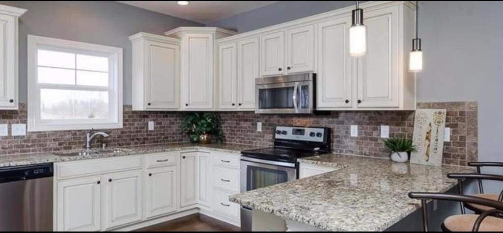 kitchen featuring a sink, a kitchen breakfast bar, stainless steel appliances, white cabinetry, and a peninsula