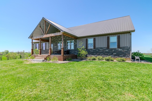 rear view of house with board and batten siding, a yard, stone siding, and metal roof