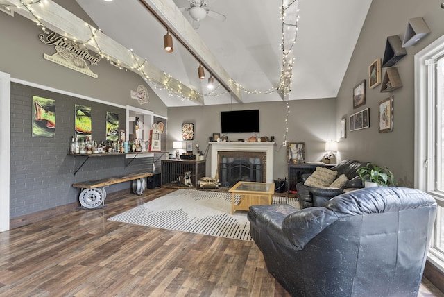 living room featuring wood finished floors, rail lighting, a fireplace, high vaulted ceiling, and a ceiling fan