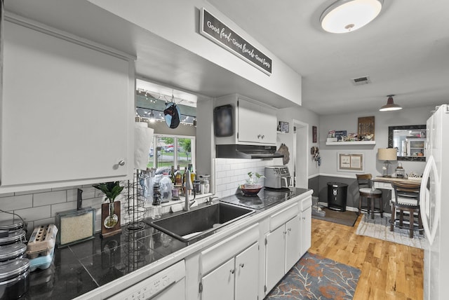 kitchen with freestanding refrigerator, white cabinets, tasteful backsplash, and light wood finished floors