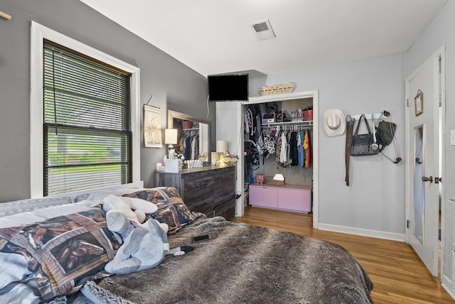 bedroom with wood finished floors, a closet, and baseboards