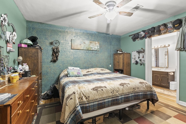 bedroom with light wood finished floors, ensuite bathroom, ceiling fan, and baseboards