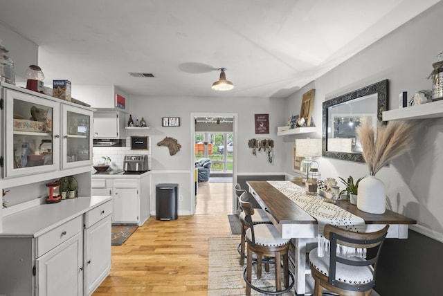 kitchen featuring open shelves, light countertops, decorative backsplash, white cabinetry, and light wood finished floors