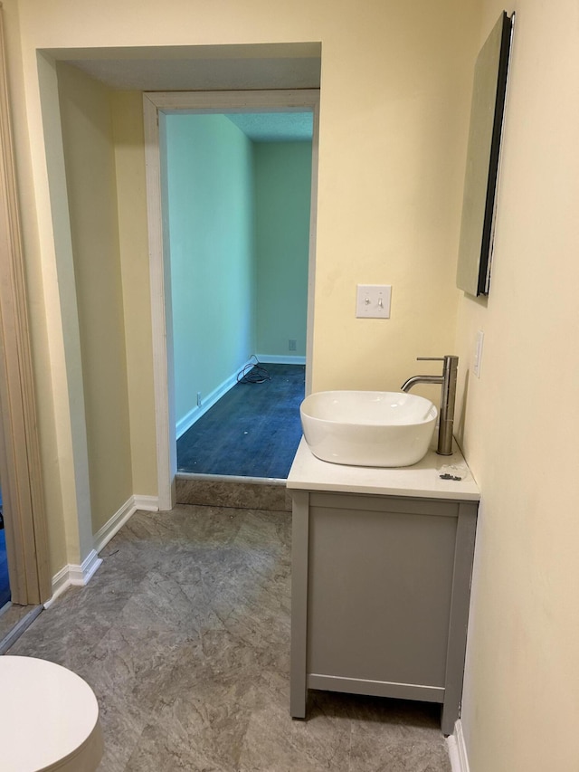 bathroom with toilet, vanity, and baseboards