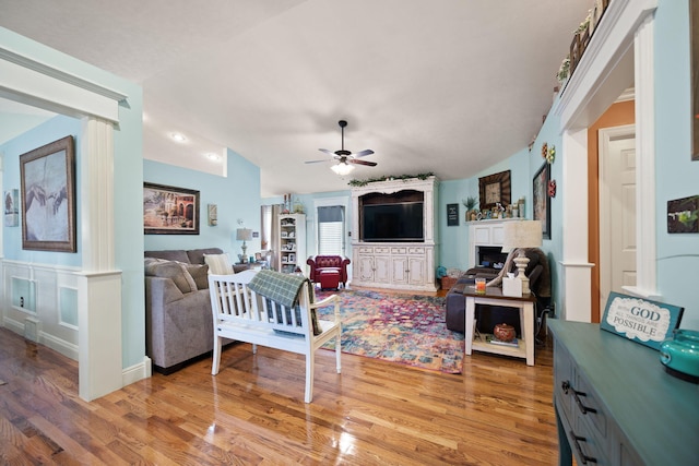 living area featuring light wood-style floors, a fireplace, and a ceiling fan