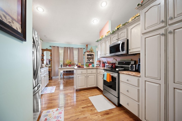 kitchen featuring a peninsula, appliances with stainless steel finishes, recessed lighting, and light wood-type flooring