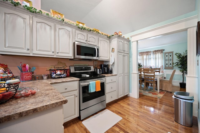 kitchen with light countertops, vaulted ceiling, stainless steel appliances, and light wood finished floors