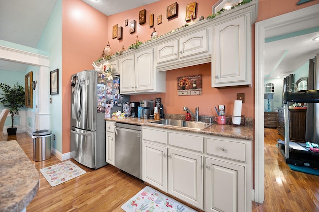 kitchen with a sink, light countertops, stainless steel appliances, and light wood finished floors