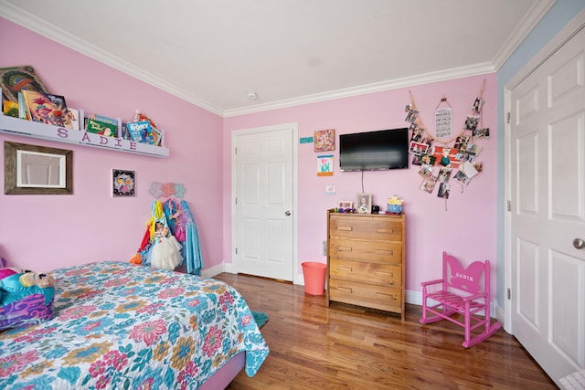 bedroom with crown molding, baseboards, and wood finished floors