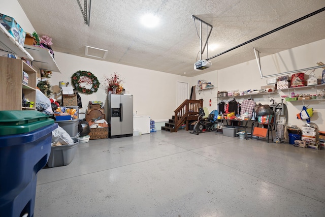 garage with stainless steel refrigerator with ice dispenser and a garage door opener