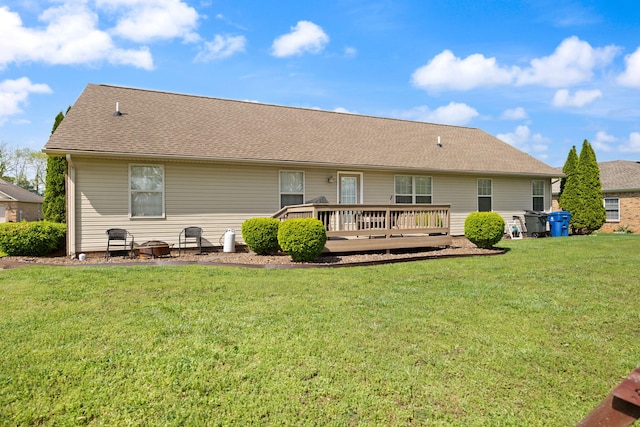 back of property featuring a lawn, roof with shingles, and a deck