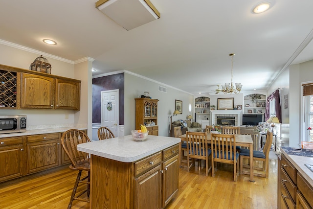 3120 Helmsdale Pl, Lexington, KY 40509 - kitchen featuring stainless steel microwave, a kitchen island, brown cabinets, light wood-style flooring, and light countertops