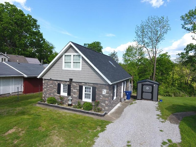 craftsman inspired home with driveway, a storage shed, an outbuilding, a front lawn, and stone siding