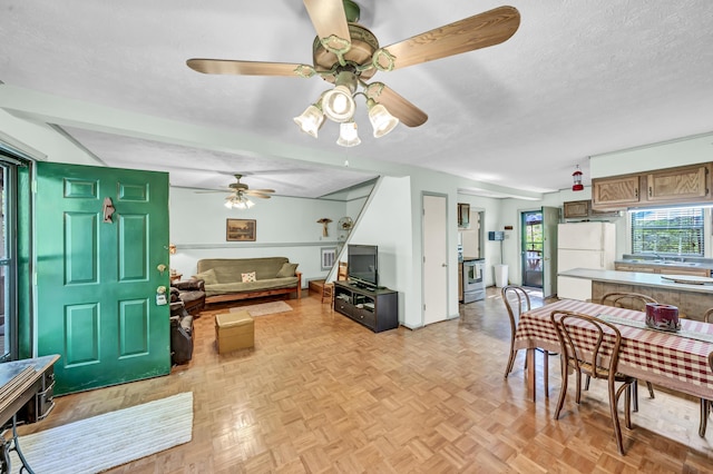 living area with a ceiling fan and a textured ceiling