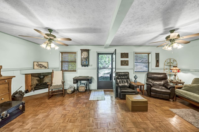 living room featuring ceiling fan, a decorative wall, and a textured ceiling