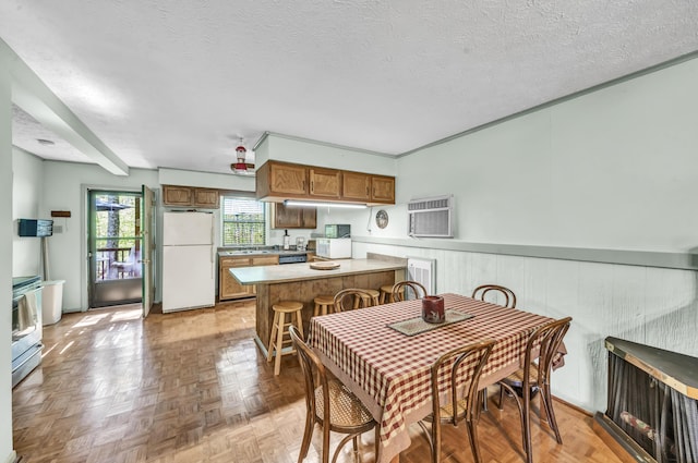 dining space featuring a textured ceiling, a wall mounted AC, and wainscoting